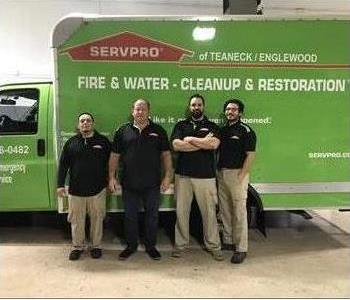 four men posing in front of green box van