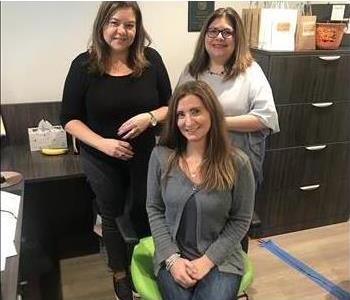 three female office staff posing in a triangle in the office