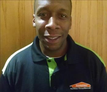 male employee posing black servpro shirt, brown background