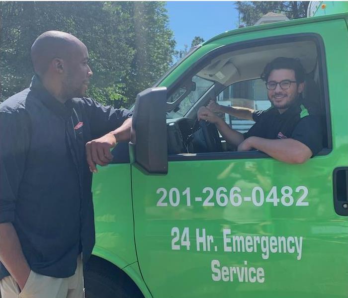An employee in a truck talking to another employee outside.